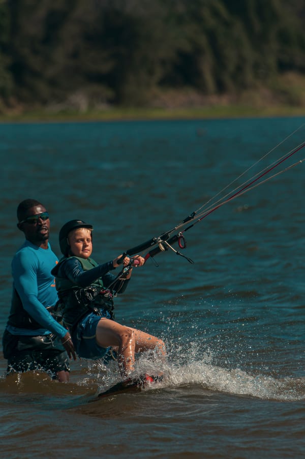 A student in helmet and vest riding the board with Wendell standing right behind